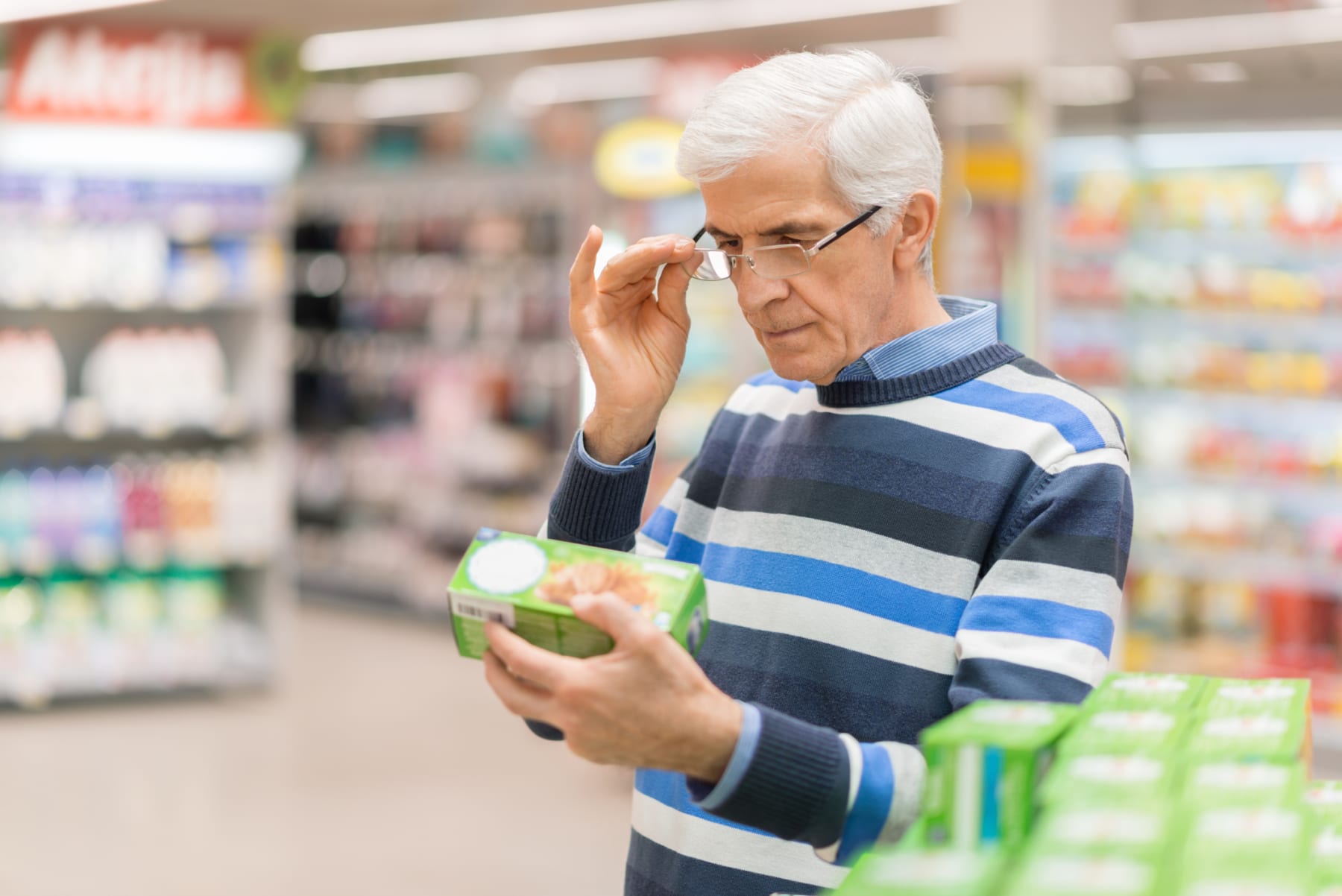 An older man checks the price of an item in-store.