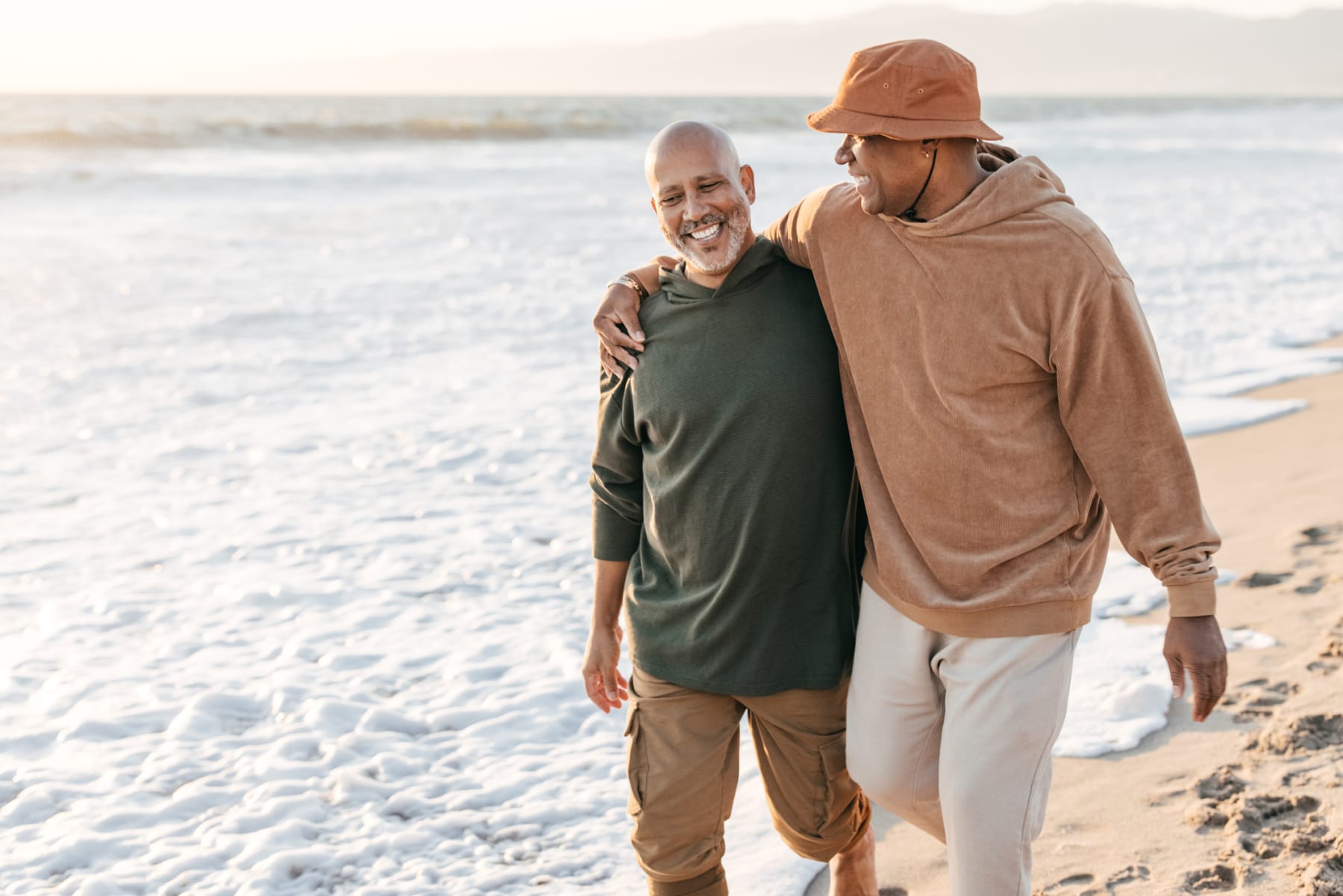 An older couple enjoys a stroll together on the beach.