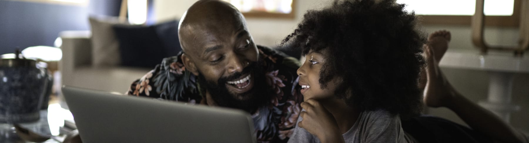 Father and daughter watch movie on laptop.